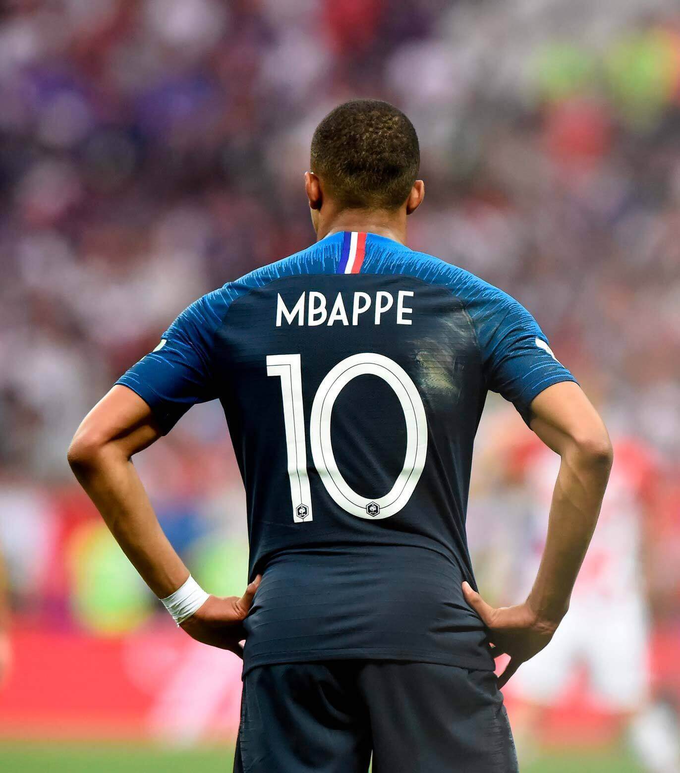 jugador de fútbol Mbappe en el campo de juego de espaldas